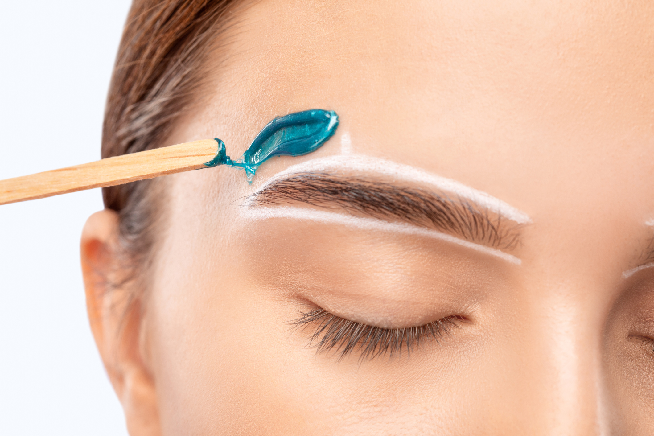 Makeup artist does facial hair removal procedure.